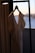 A close-up of a beautifully designed dress hanging on a wooden hanger against a soft, neutral background.