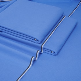 Folded navy blue fabric with subtle patterns, arranged neatly on a wooden surface with traditional accessories.