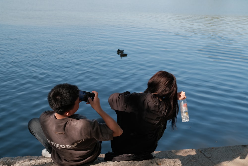 a man and a woman taking a picture of a duck in the water