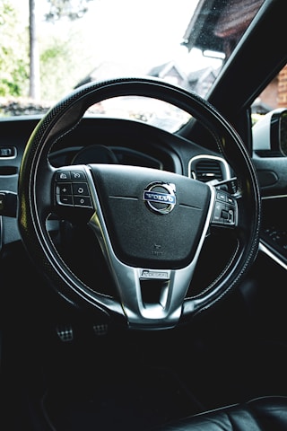 Close-up of hands on a steering wheel inside a sleek car interior.