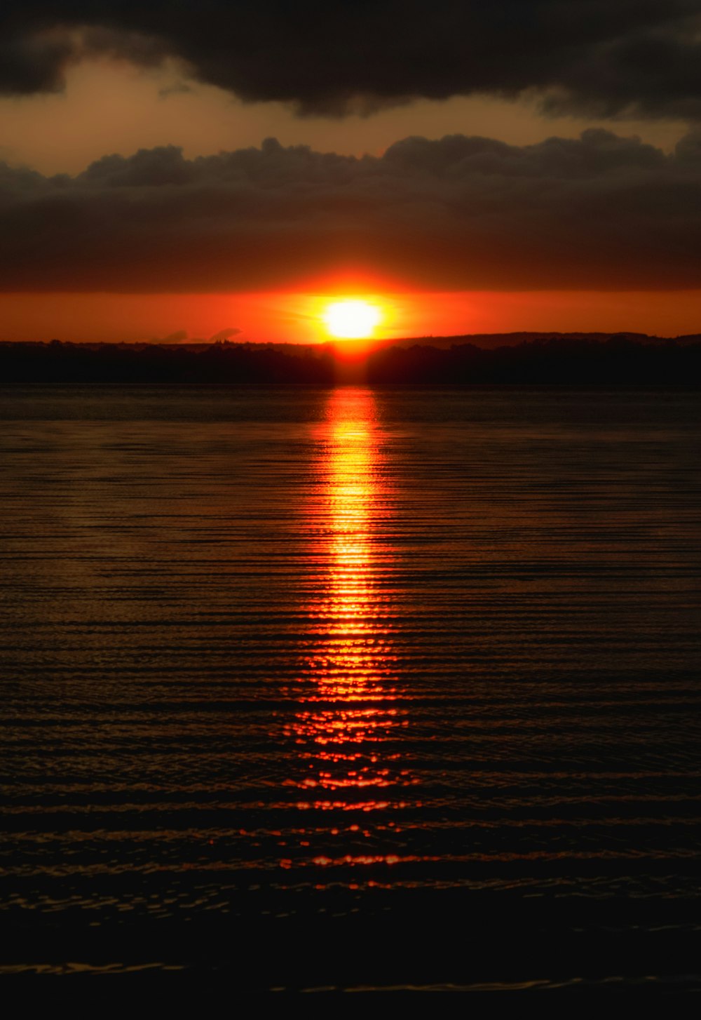 a large body of water with a sunset in the background