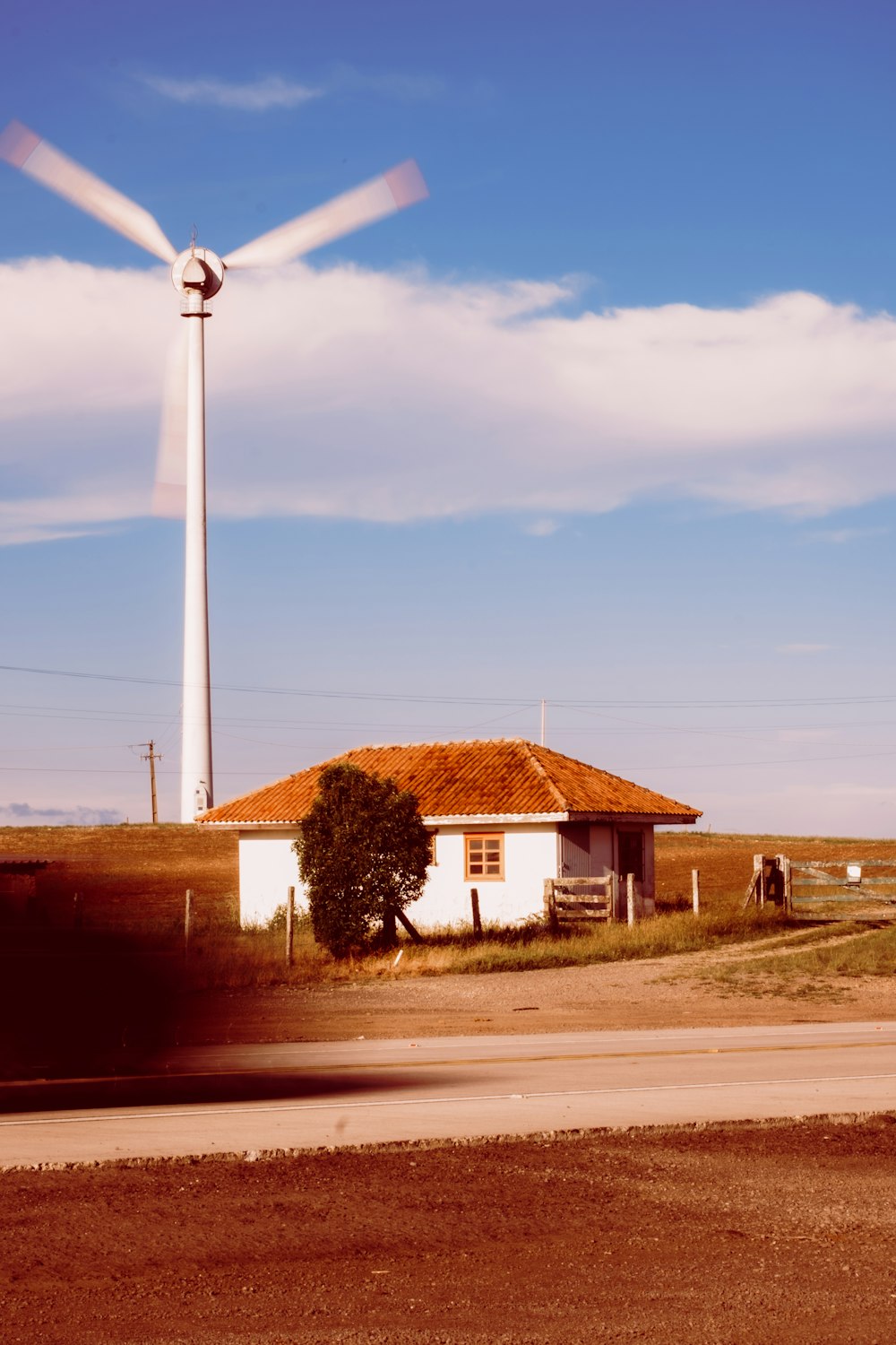 un moulin à vent au loin avec une maison au premier plan