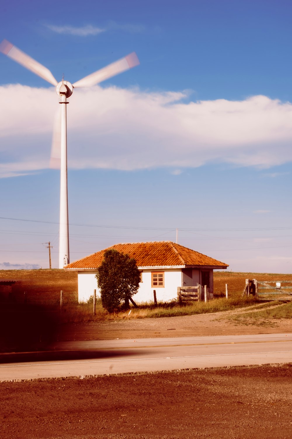 eine Windmühle in der Ferne mit einem Haus im Vordergrund