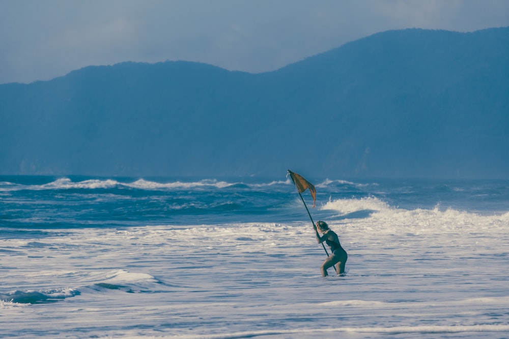 a man holding a flag while standing in the ocean