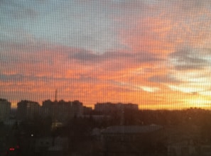 A city skyline viewed from a high-rise office window during sunset.