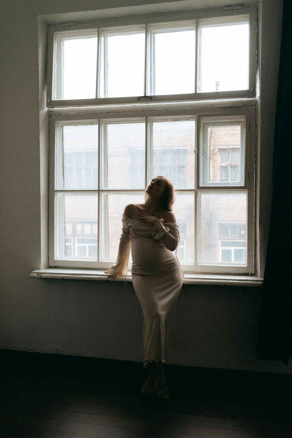 a pregnant woman standing in front of a window