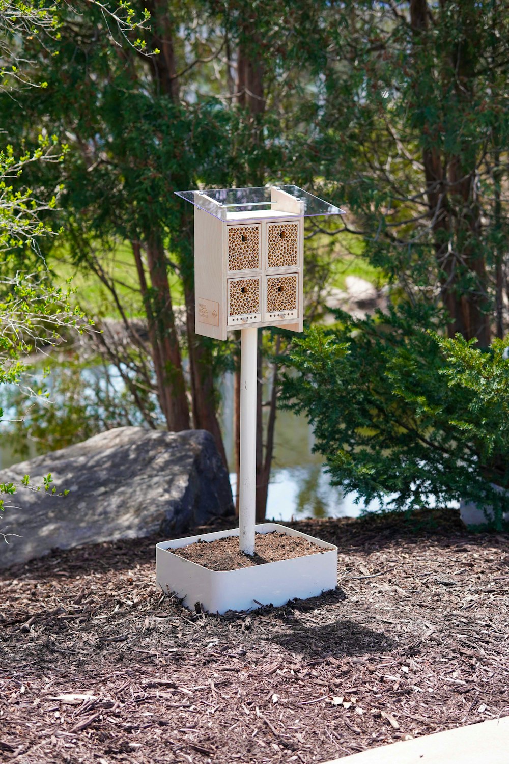 a bird feeder sitting on top of a white pole