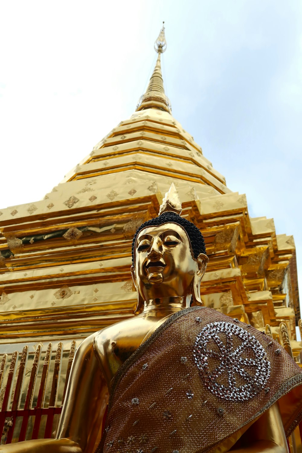 a golden buddha statue in front of a golden pagoda