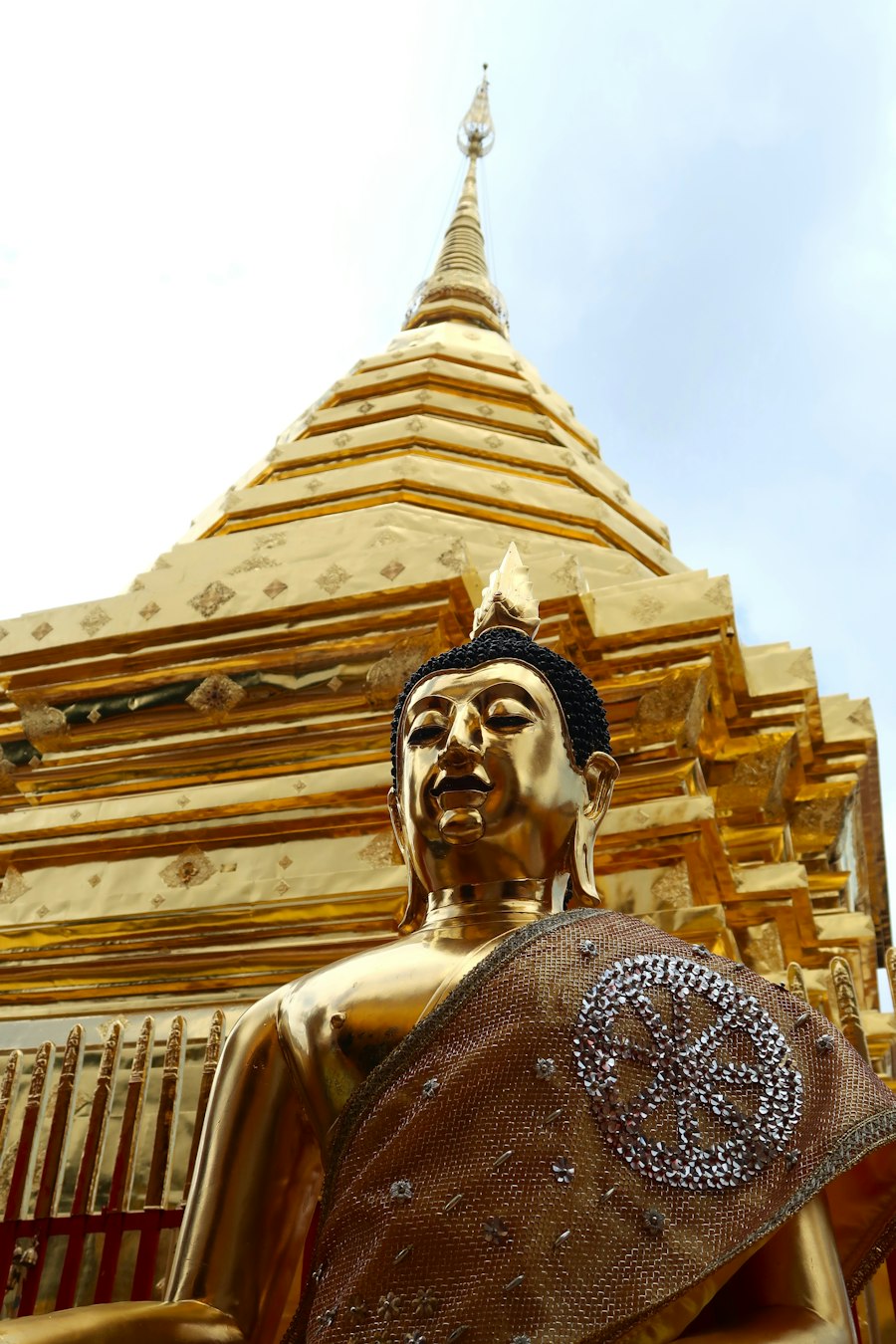 Golden Buddha statue in front of a golden pagoda in Chiang Mai