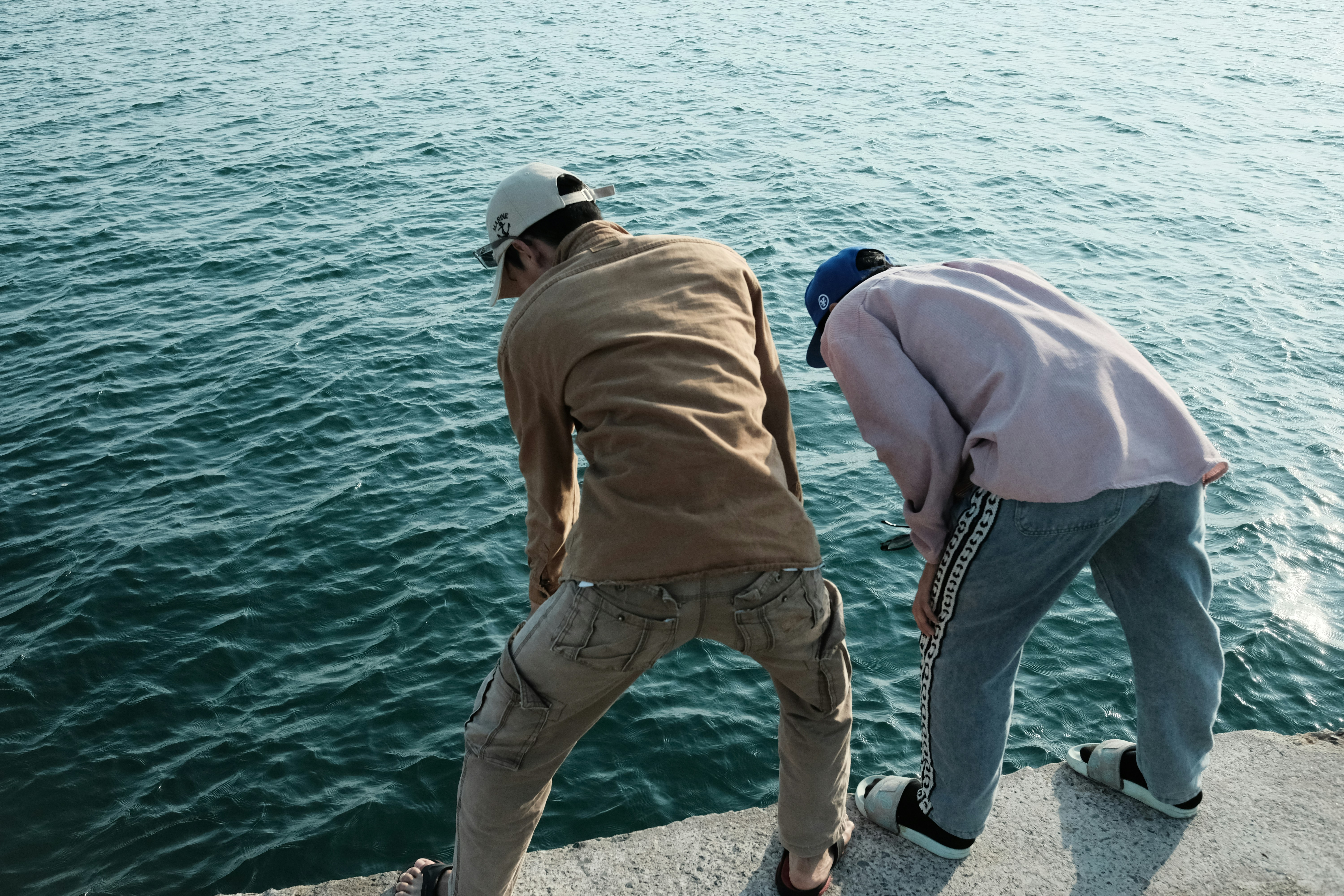 a couple of men standing next to a body of water
