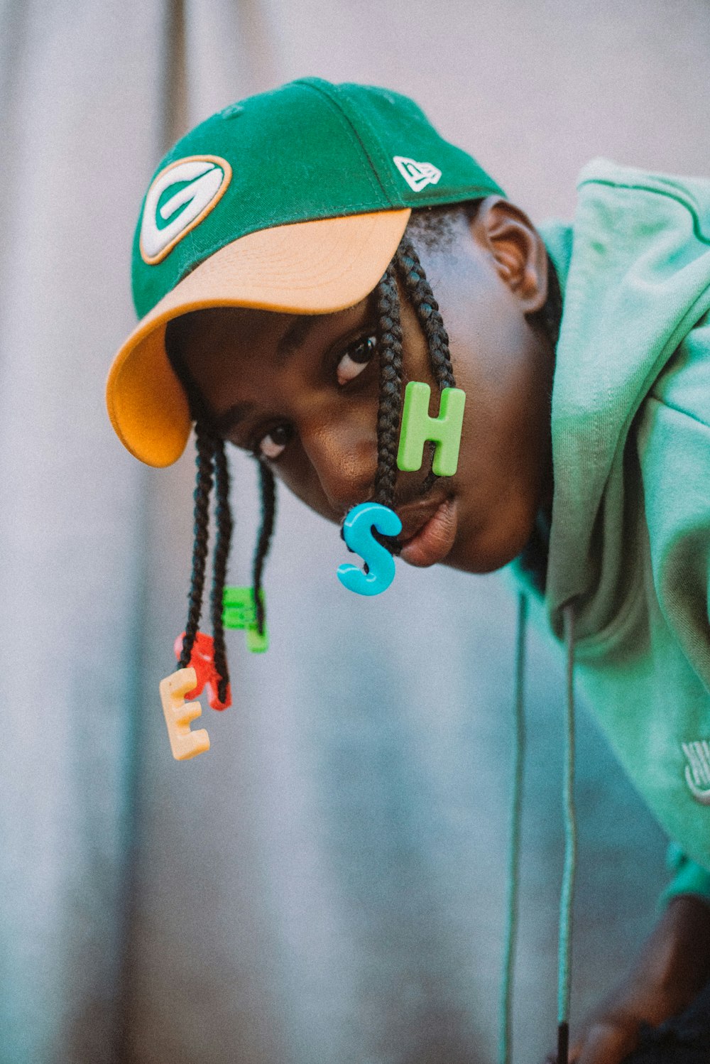 a young boy wearing a green hat with the word h on it