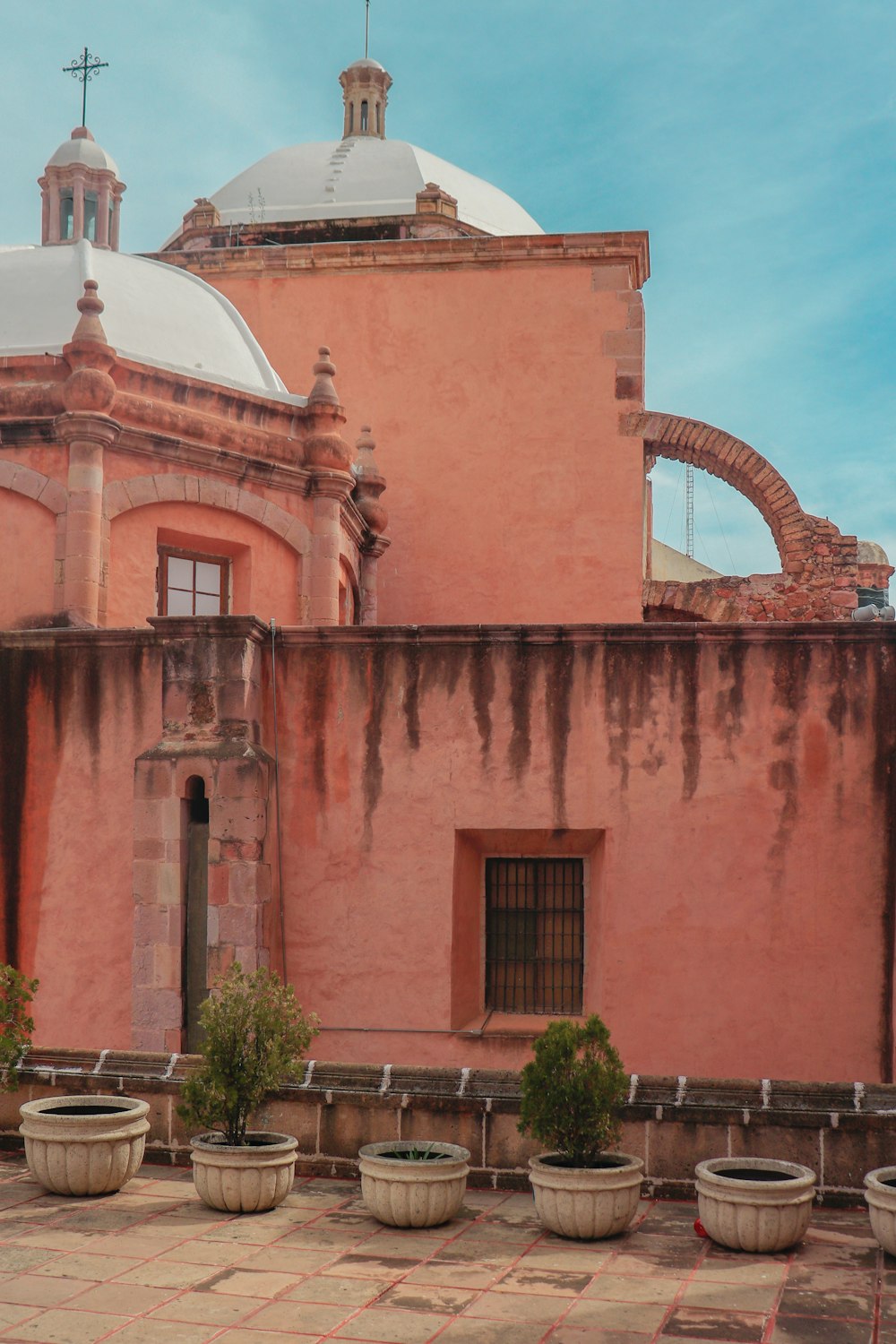 a pink building with potted plants in front of it