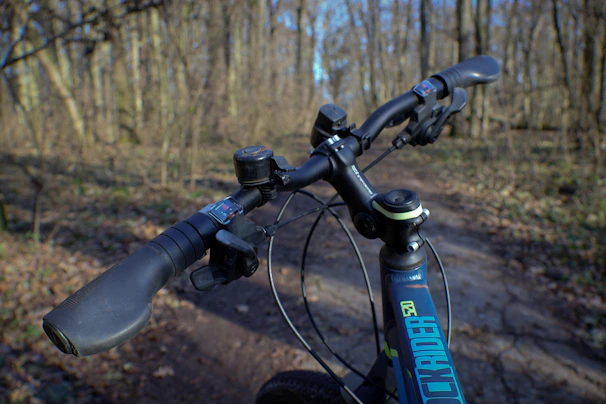 Close-up of a cyclist’s hands gripping the handlebars with a blurred forest background
