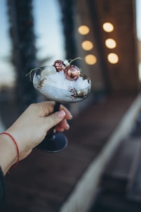 Close-up of a handcrafted snow globe flask sparkling with delicate rose gold accents against a soft pink background.