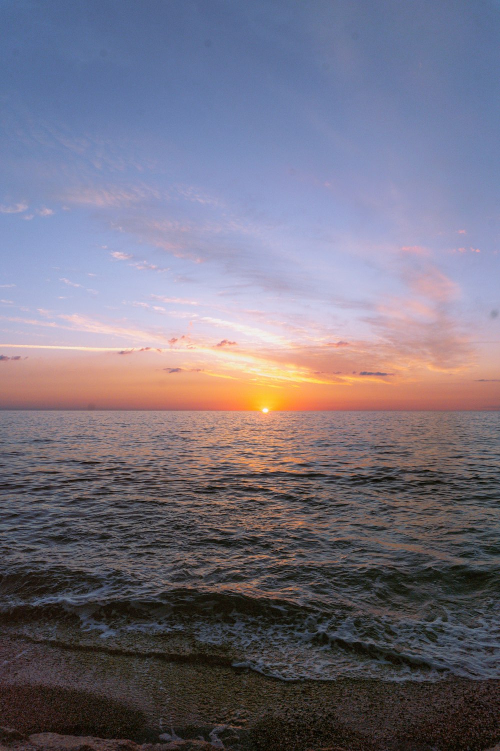 the sun is setting over the water at the beach