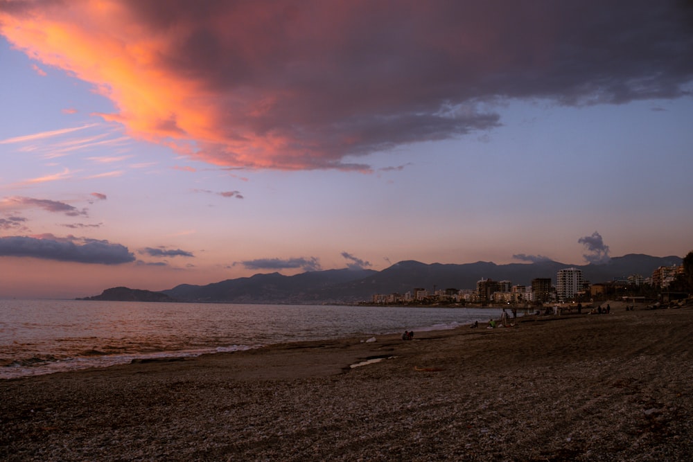 a sunset view of a beach with mountains in the background