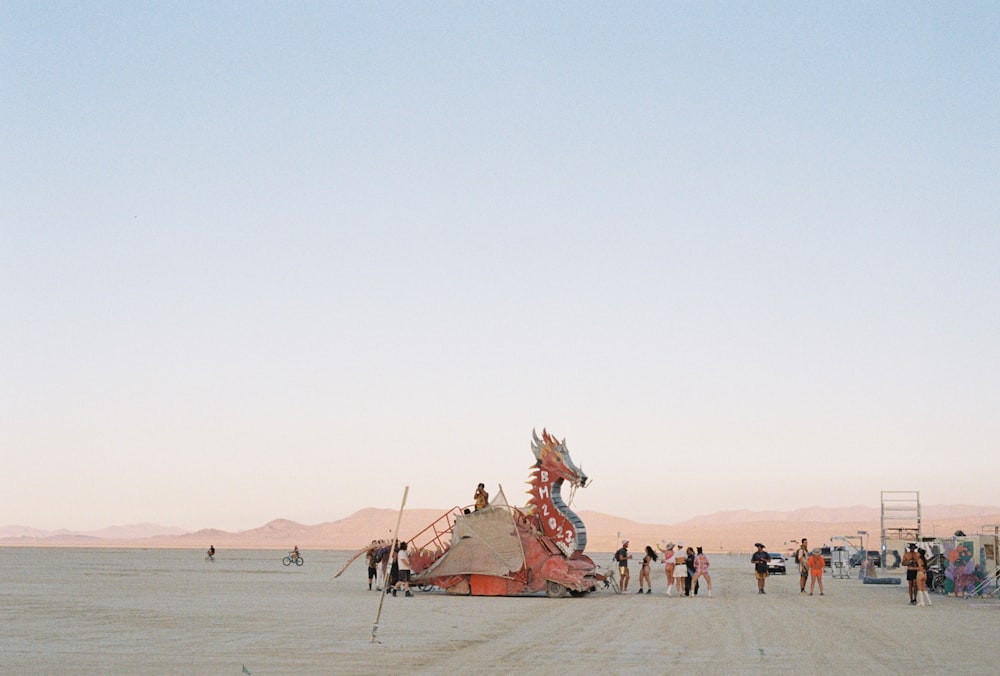 a group of people standing around a structure in the middle of a desert