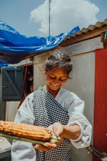Smiling vendor handing over a wrapped pamonha to a happy customer