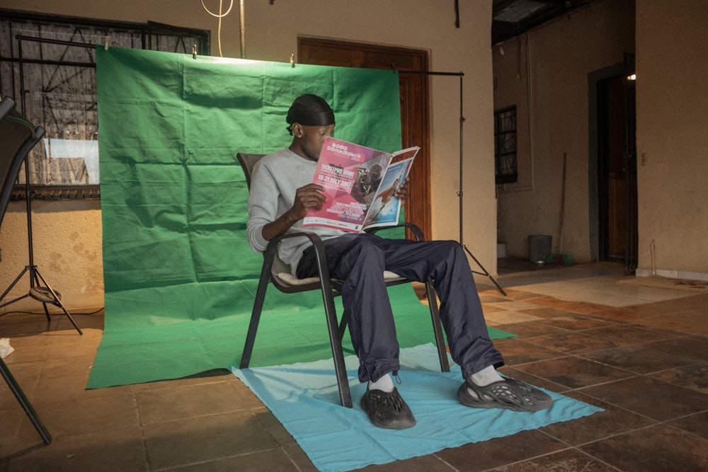 a man sitting in a chair reading a magazine