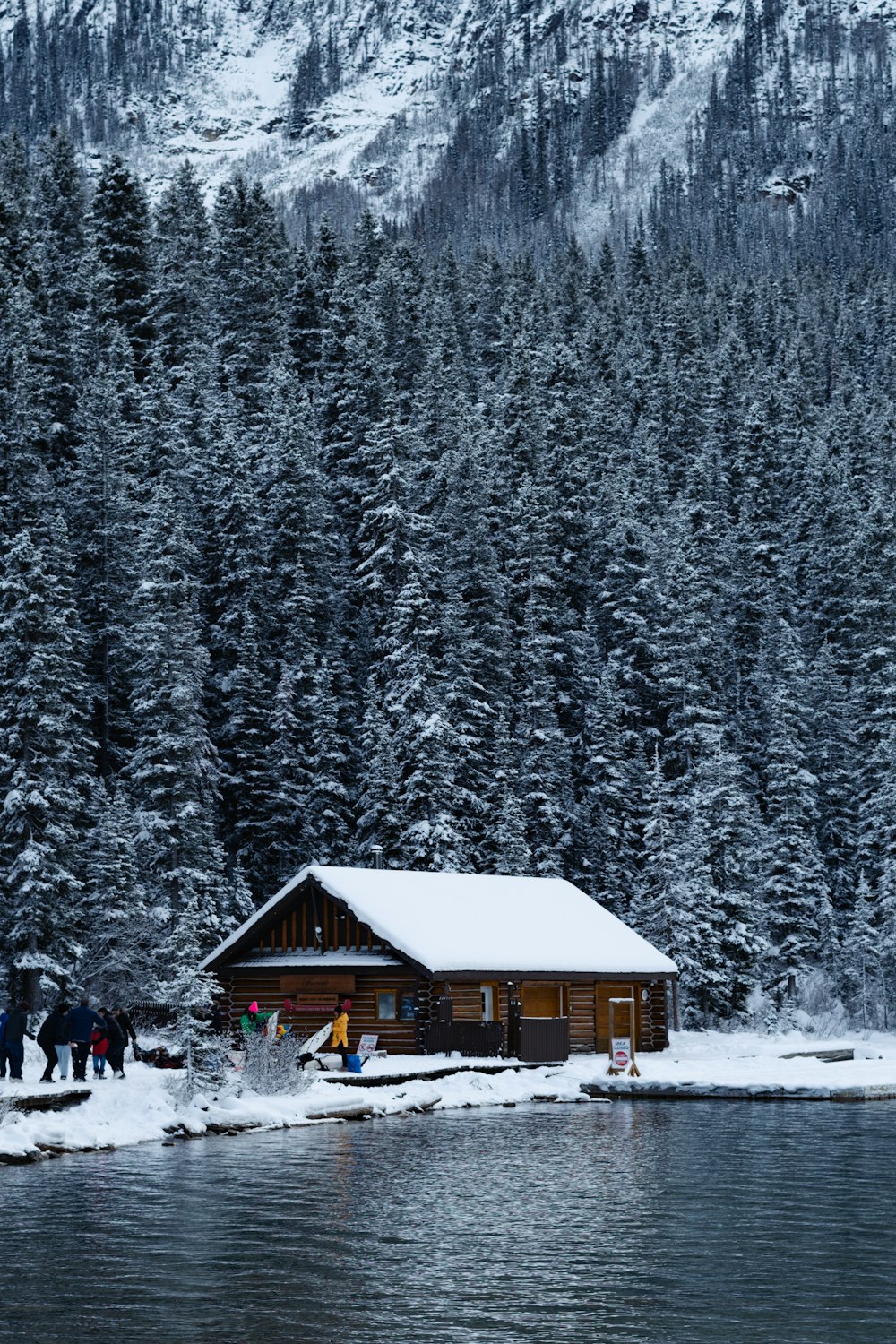 a group of people standing outside of a cabin in the snow