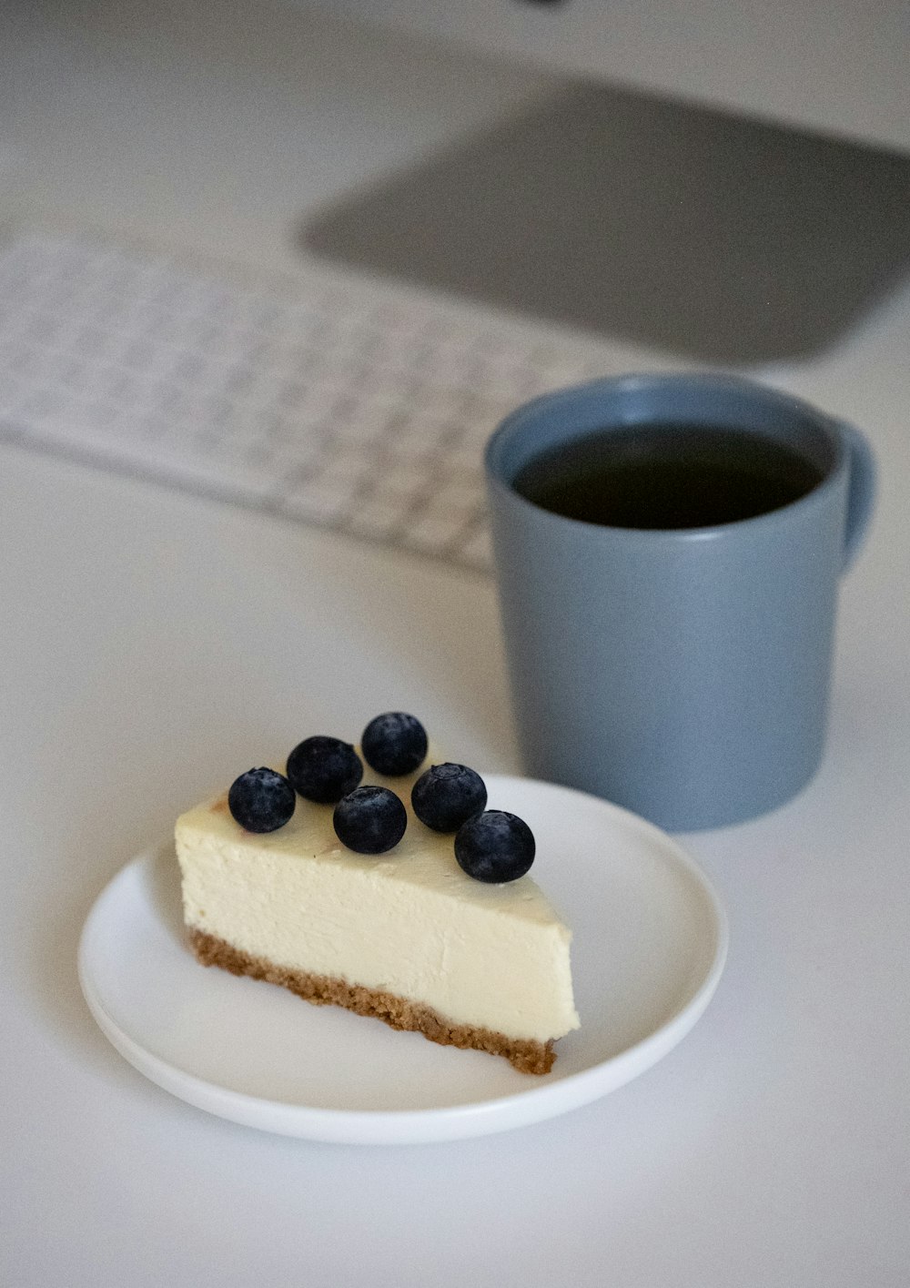 a piece of cheesecake on a plate next to a cup of coffee