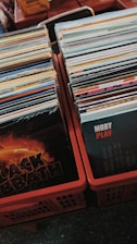 Stacks of vinyl records are neatly arranged in plastic crates. The front covers of two albums, one by Black Sabbath and another by Moby, are prominently visible, suggesting a collection of diverse music genres.