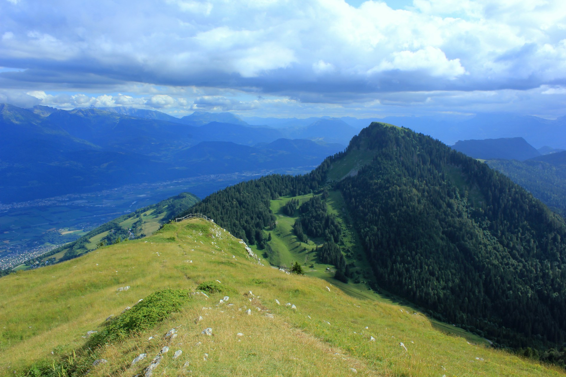 a view of a grassy hill with mountains in the background