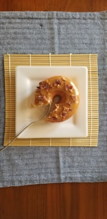 Close-up of a hearty maple bacon donut resting on a wooden slab with pine needles scattered around
