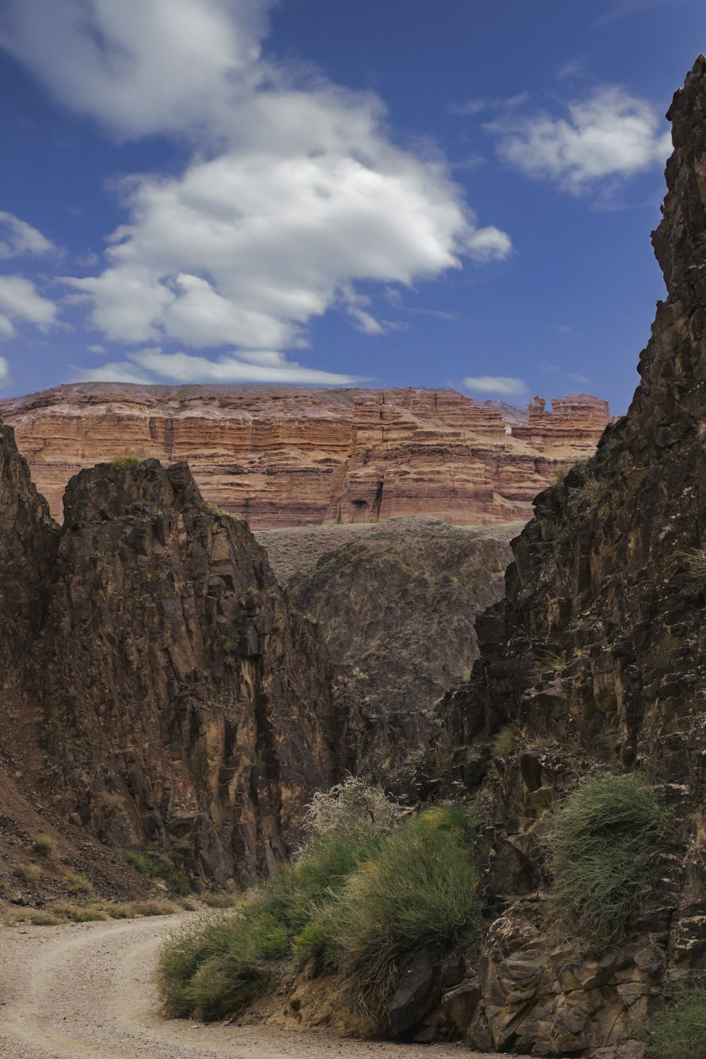 a dirt road going through a canyon with a mountain in the background