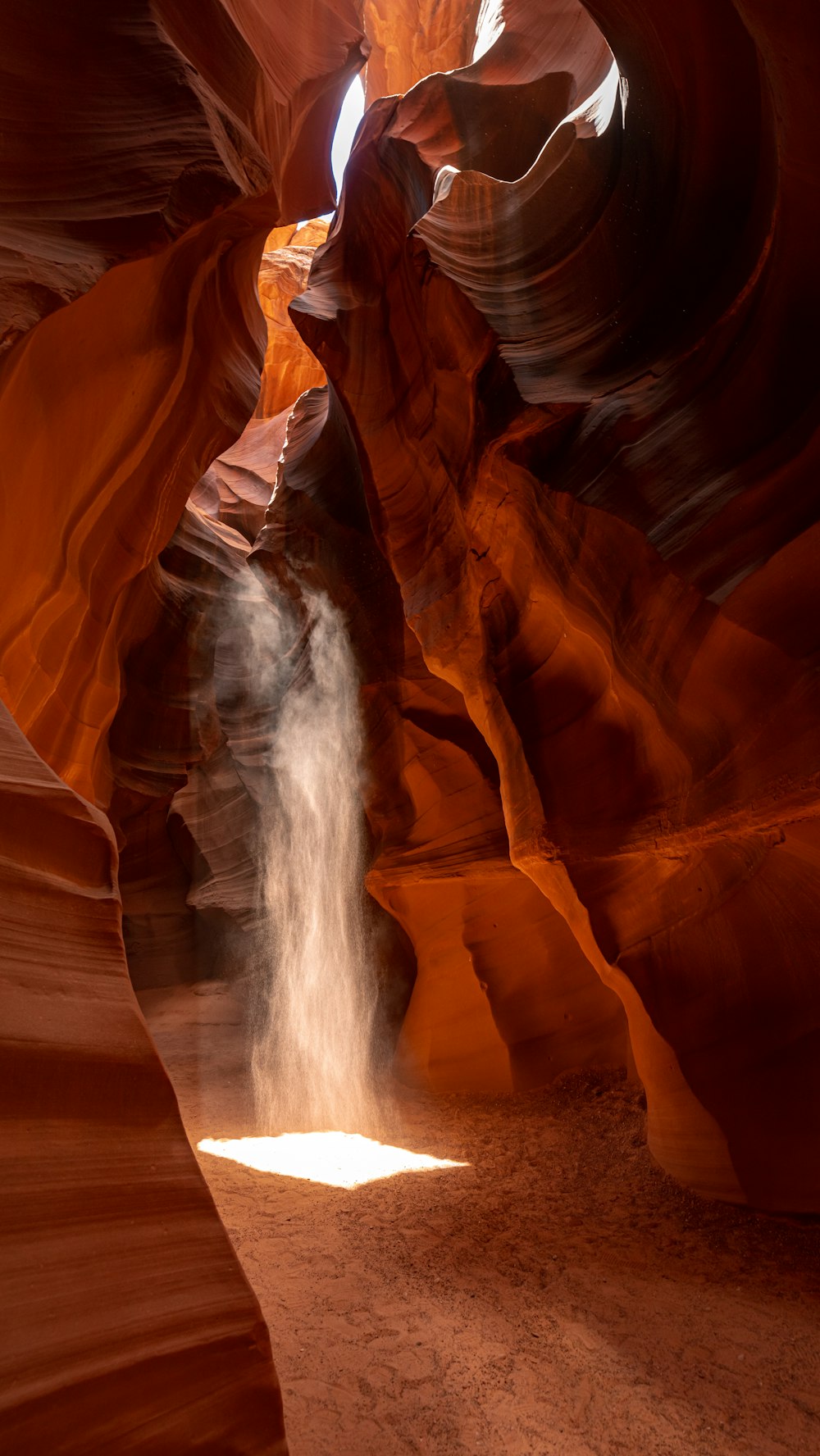 a narrow canyon with a waterfall coming out of it