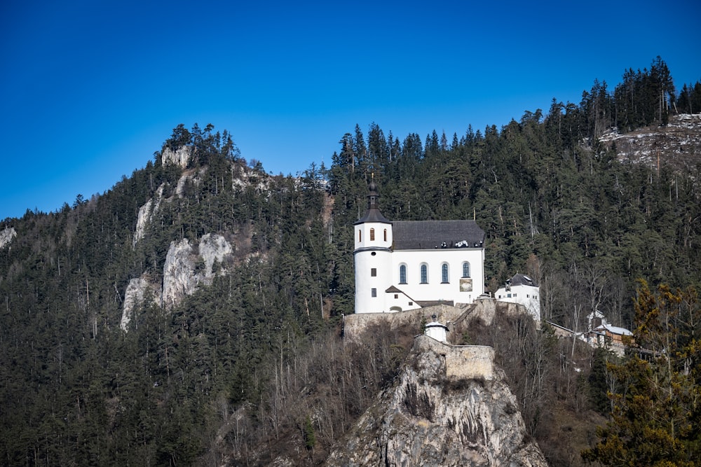 a white church on a cliff with a mountain in the background