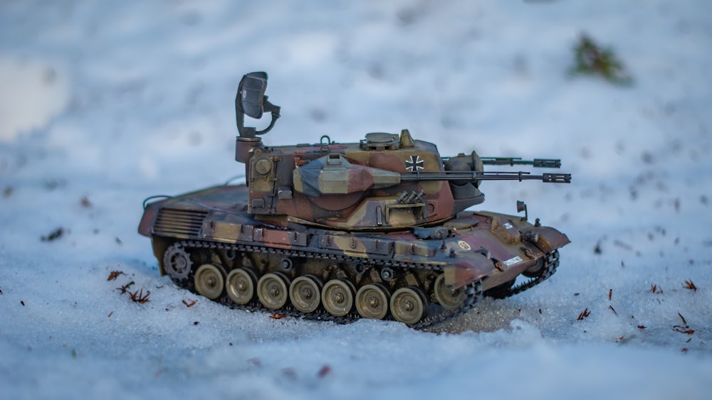 a toy army tank sitting in the snow