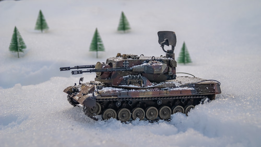 un carro armato giocattolo nella neve con alberi sullo sfondo