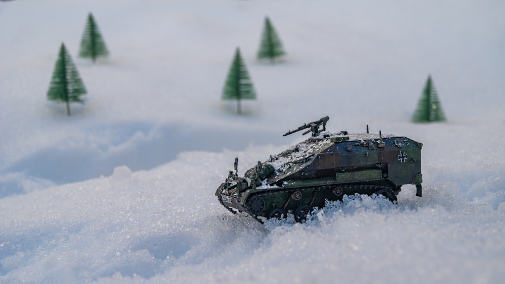a toy tank in the snow with trees in the background