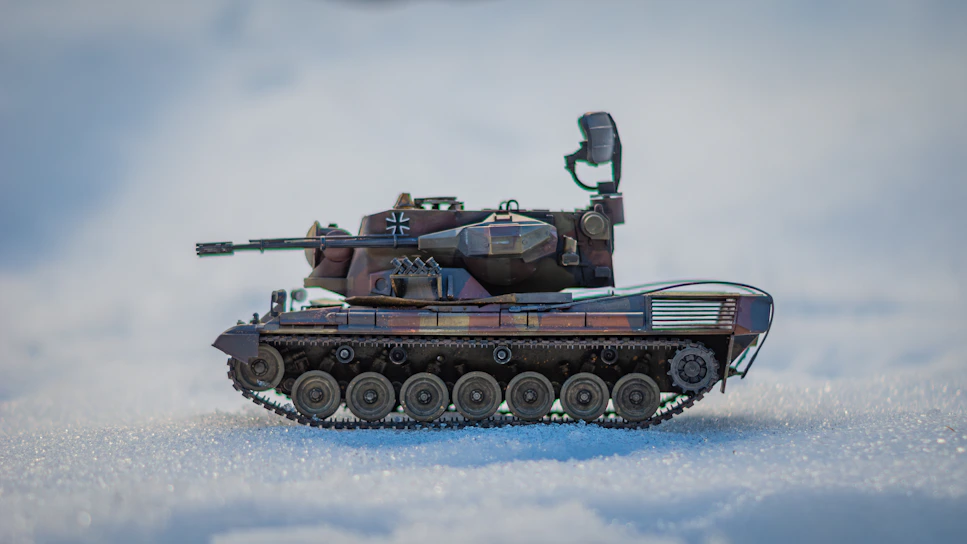 A sleek, high-tech military tank rolling through a digital battlefield with camouflage patterns blending into the background.