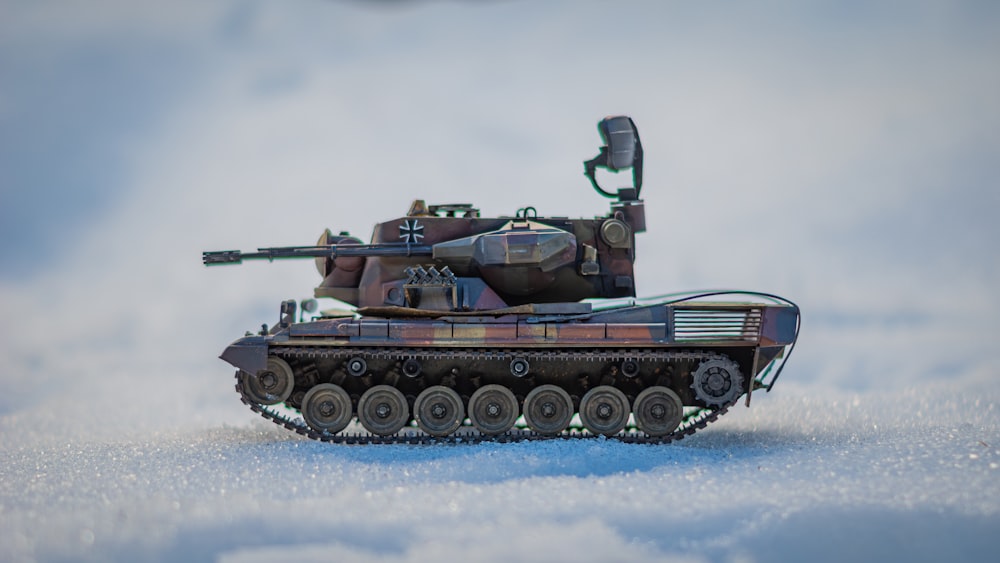 a toy army tank sitting in the snow