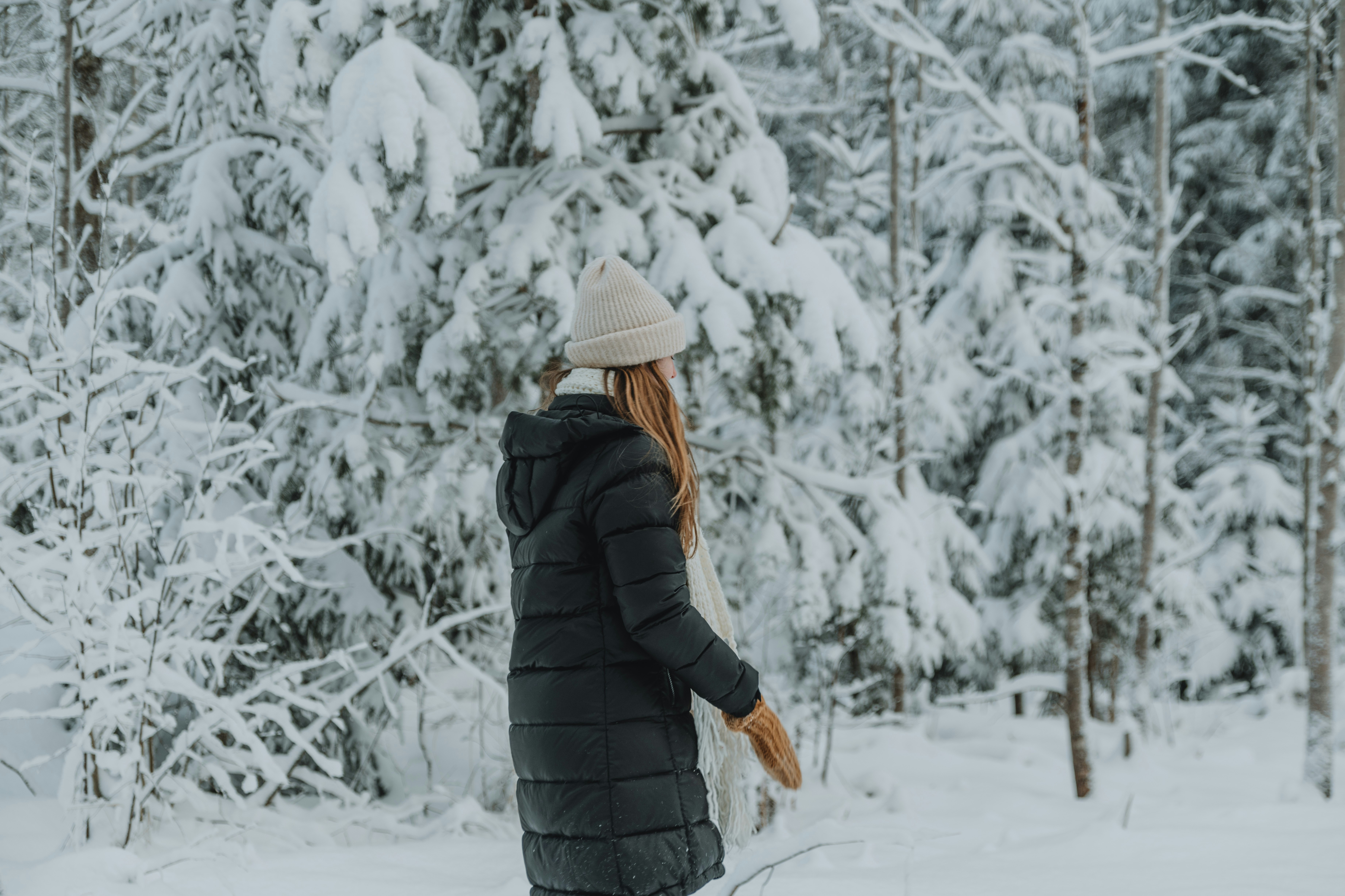 a woman walking through a snow covered forest