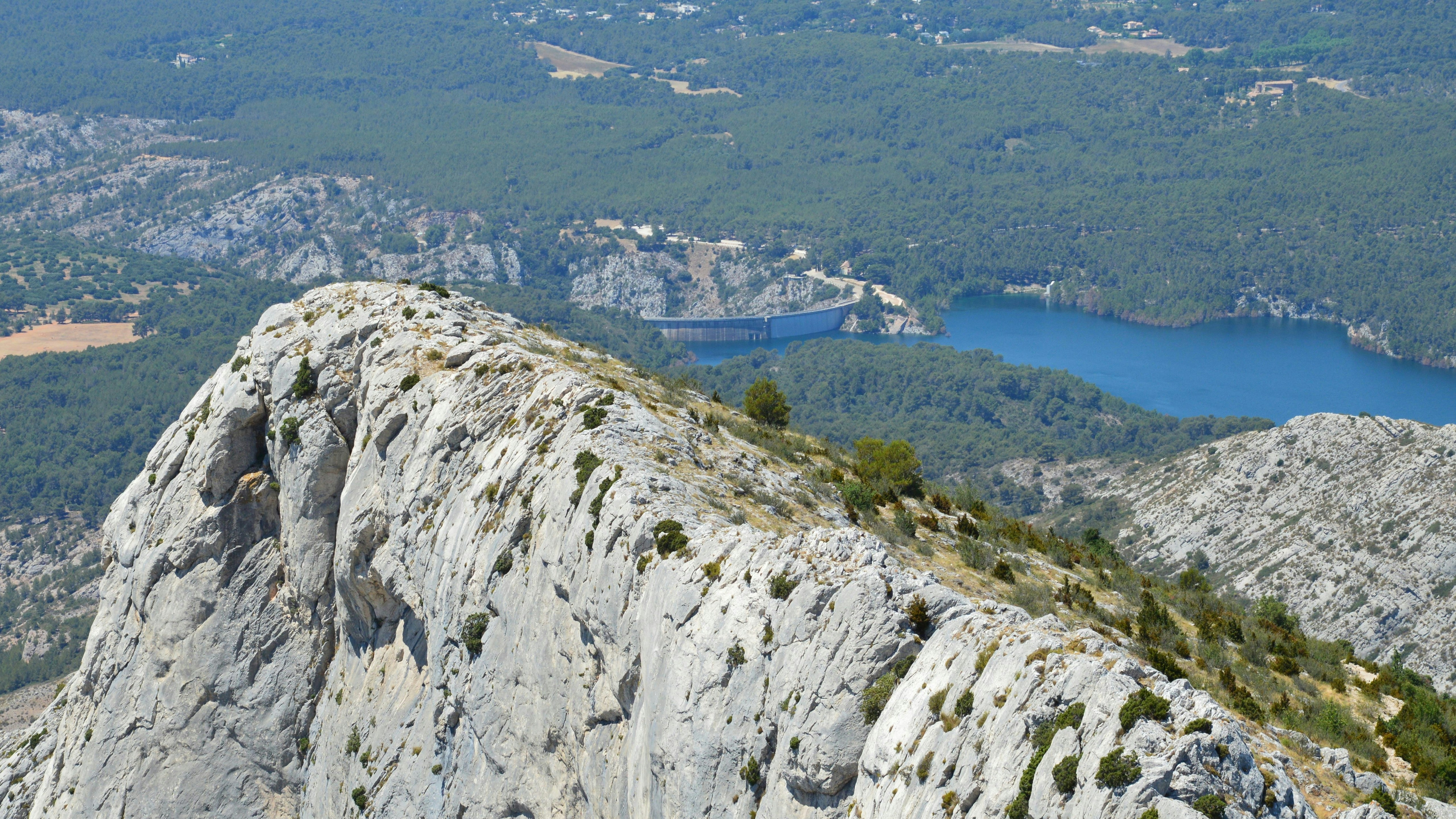 a person standing on top of a mountain next to a lake