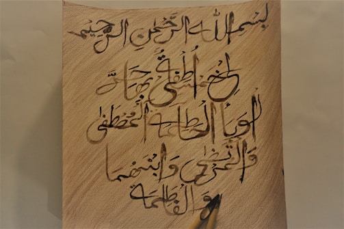 Close-up of a pen resting on a page filled with Arabic script from the Gaijin story.