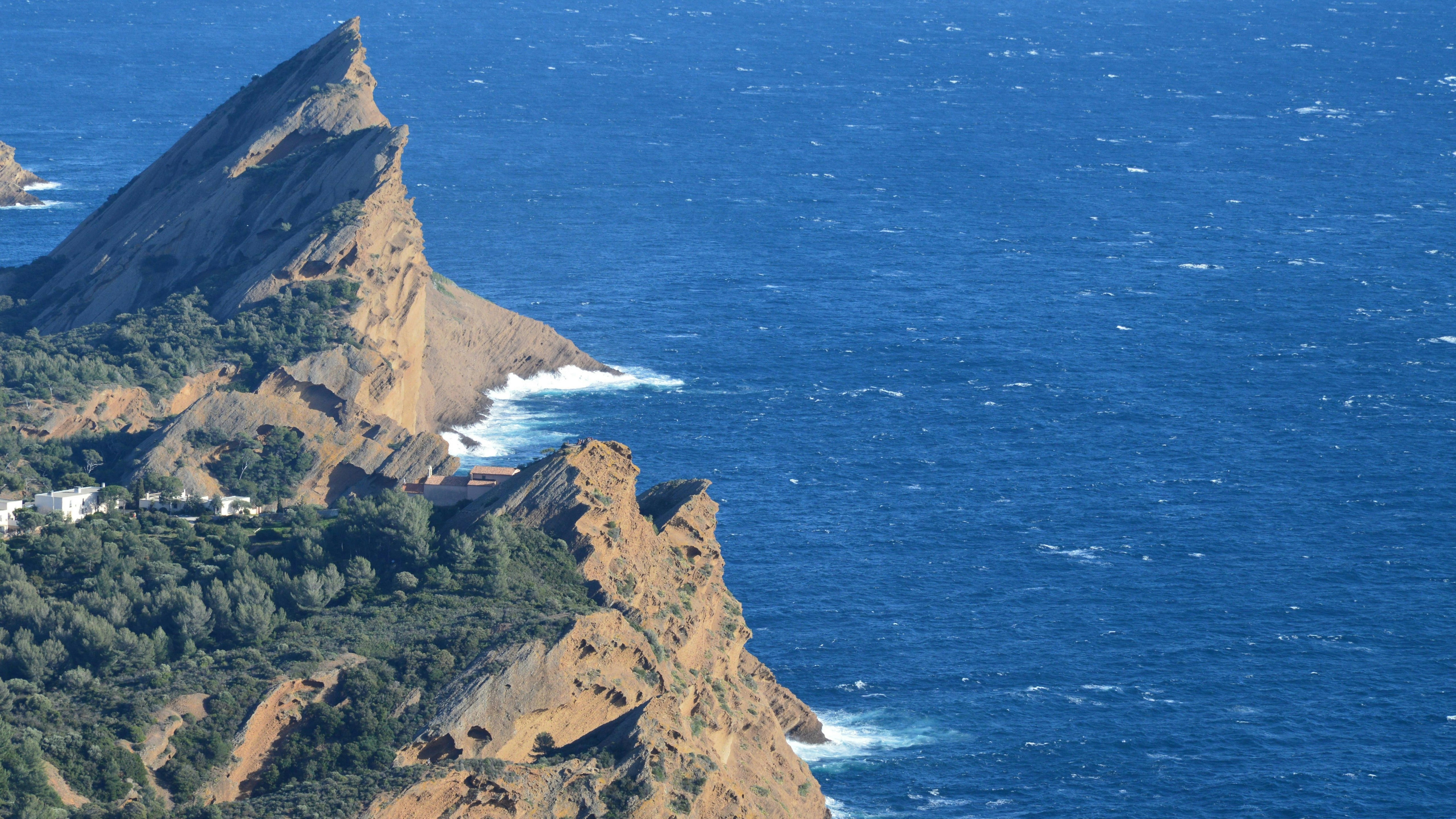 a mountain with a house on top of it next to the ocean
