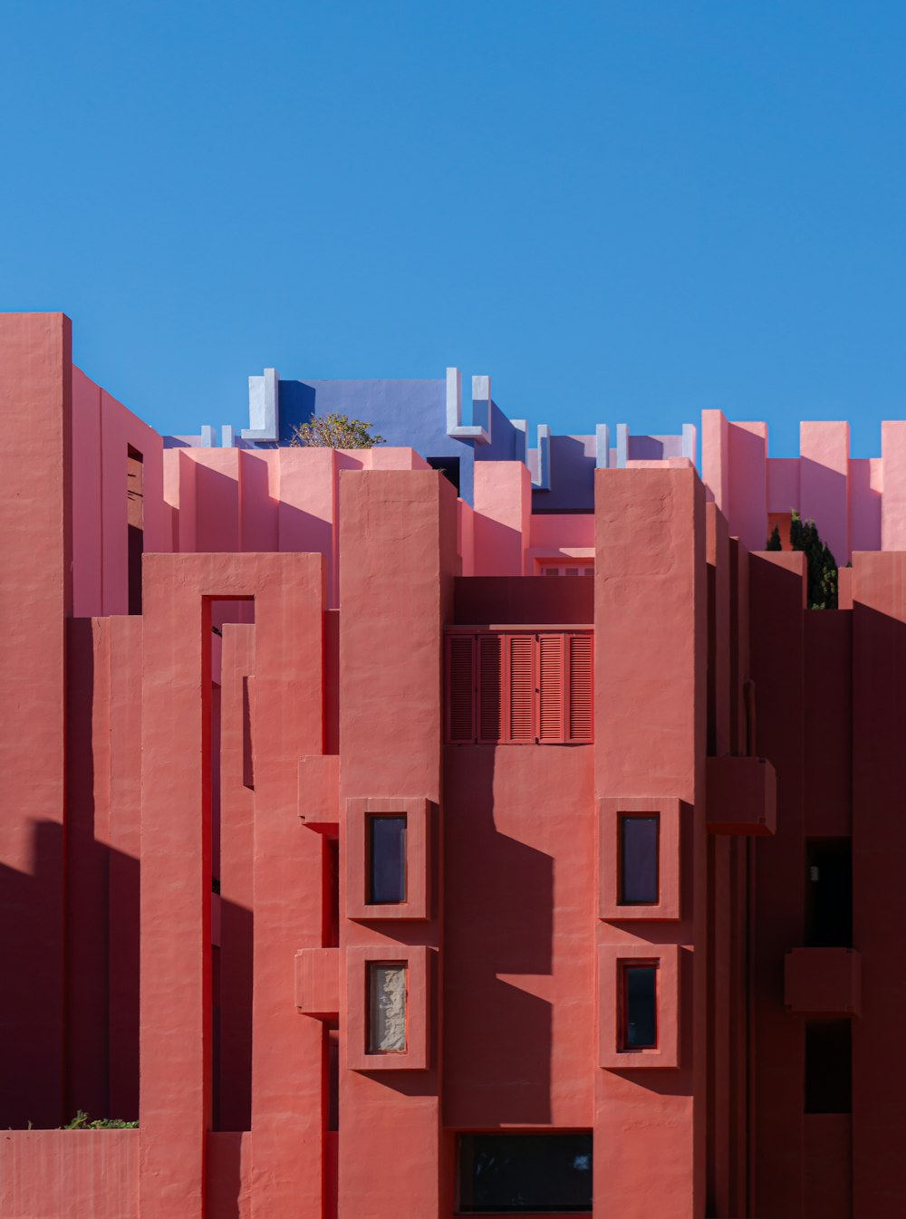 a red building with many windows and a sky background