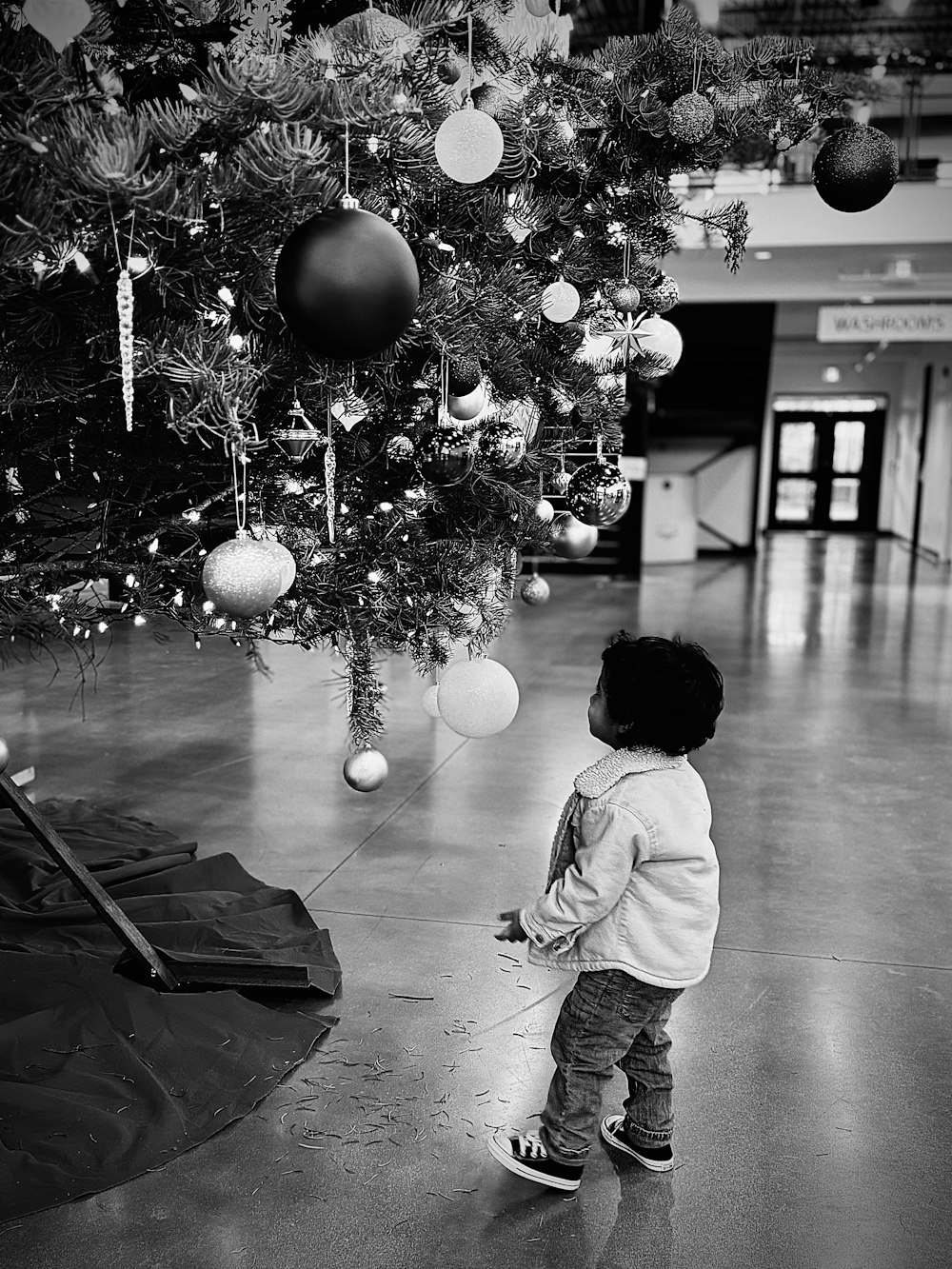 Un niño pequeño parado frente a un árbol de Navidad
