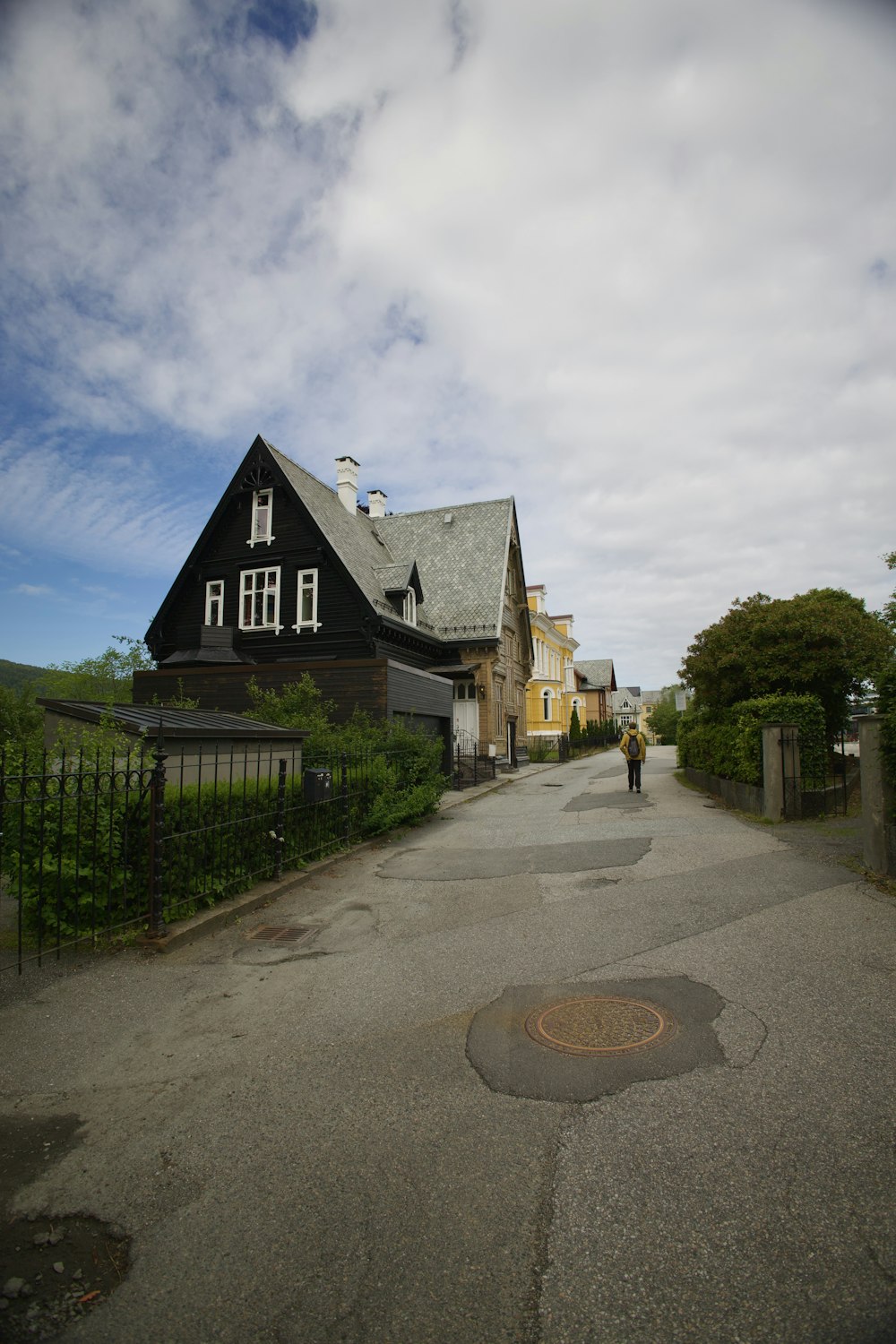 a person walking down a street in front of a house