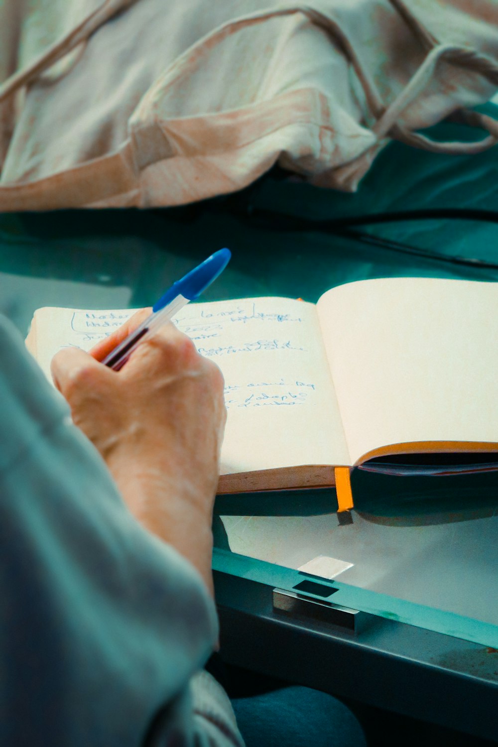 una persona sentada en una mesa con un cuaderno y un bolígrafo