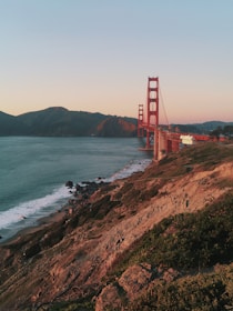 Golden Gate Bridge at sunset with soft orange hues reflecting on the water below.