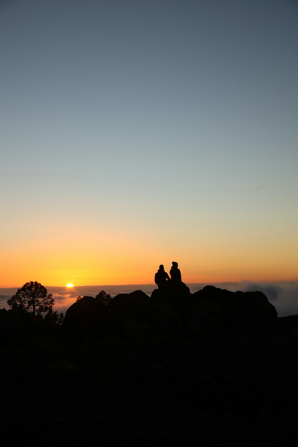 a couple of people sitting on top of a mountain