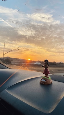 A close-up of a car dashboard decorated with tropical flower garlands and sunlight streaming through the window.