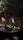 A dimly lit bar with a rustic atmosphere. Overhead, green foliage and hanging red ribbons create a dramatic ceiling display. The bartender is preparing drinks behind a counter filled with bottles and utensils. Warm lighting enhances the cozy ambiance, while patrons sit at the counter.