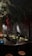 A dimly lit bar with a rustic atmosphere. Overhead, green foliage and hanging red ribbons create a dramatic ceiling display. The bartender is preparing drinks behind a counter filled with bottles and utensils. Warm lighting enhances the cozy ambiance, while patrons sit at the counter.
