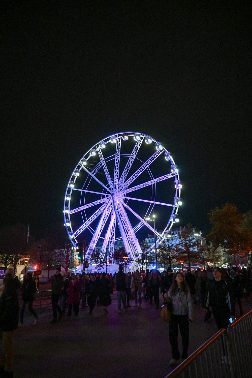 Une foule de gens debout autour d’une grande roue la nuit